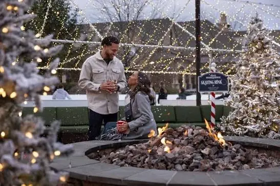 Fire tables and flocked trees under string lights in the winter village