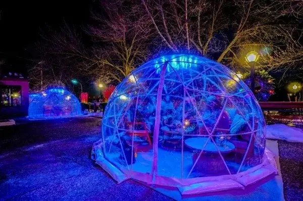 Clear-dome igloos glowing at night in the winter village