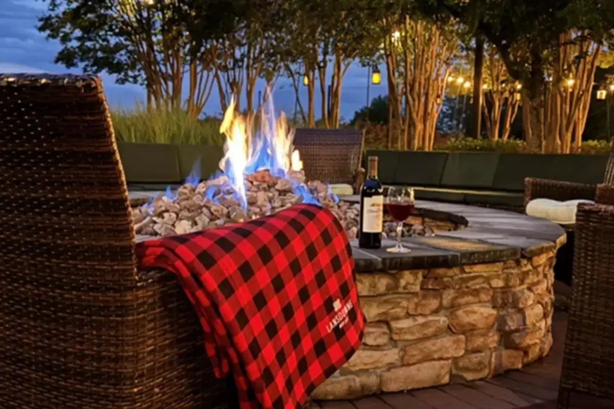Stone firepit at dusk with a plaid blanket and a glass of wine