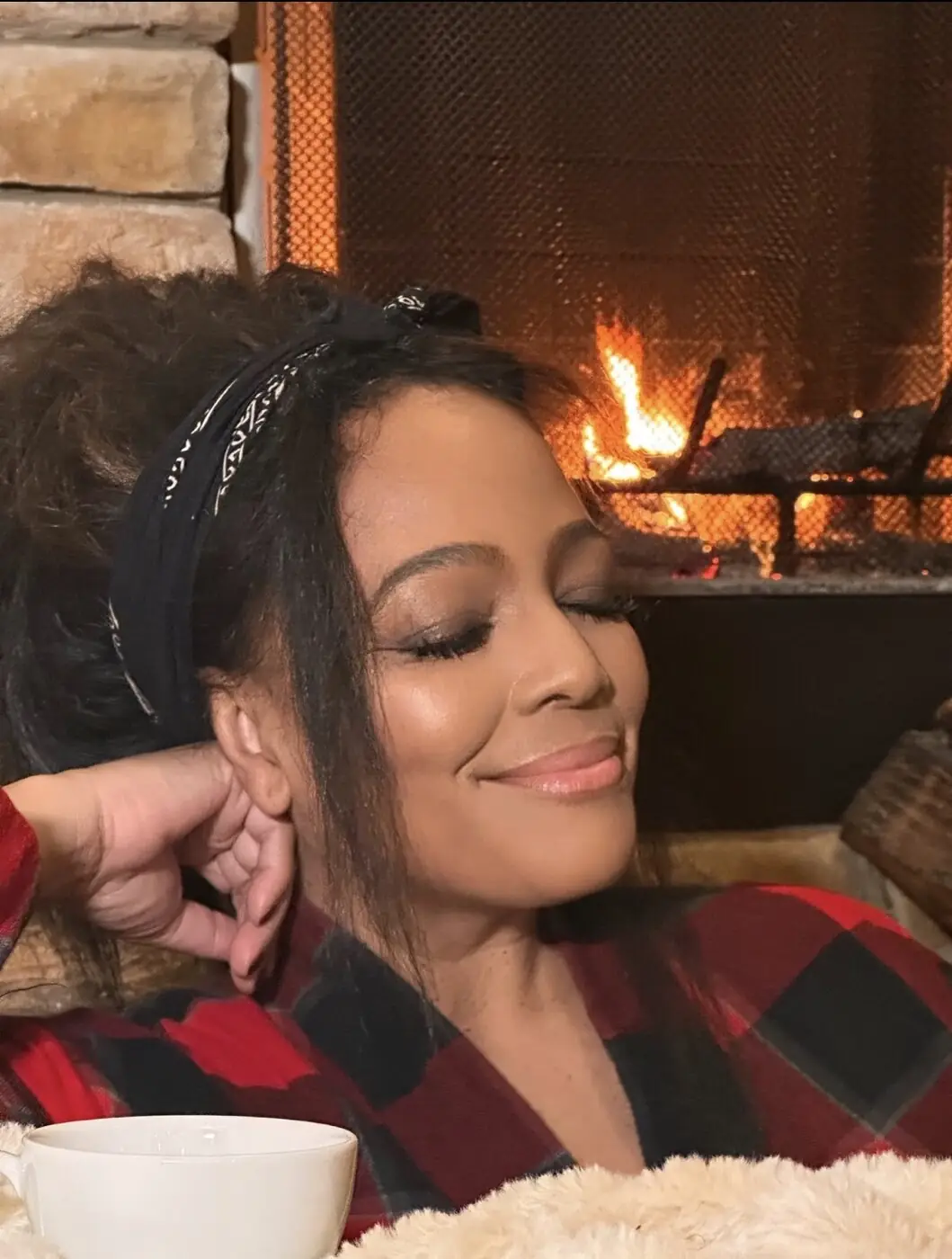 Kim Fields fireside, eyes closed and smiling, at the Winter Edit